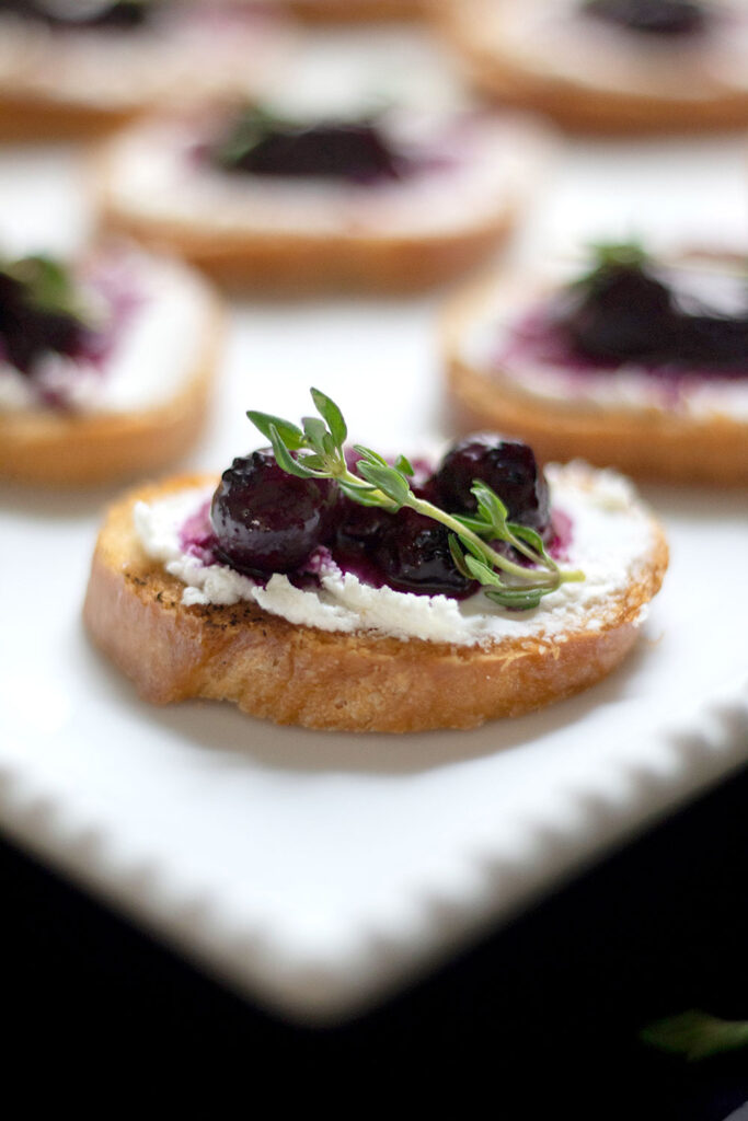 close up of a crostini topped with goat cheese and blueberry compote.