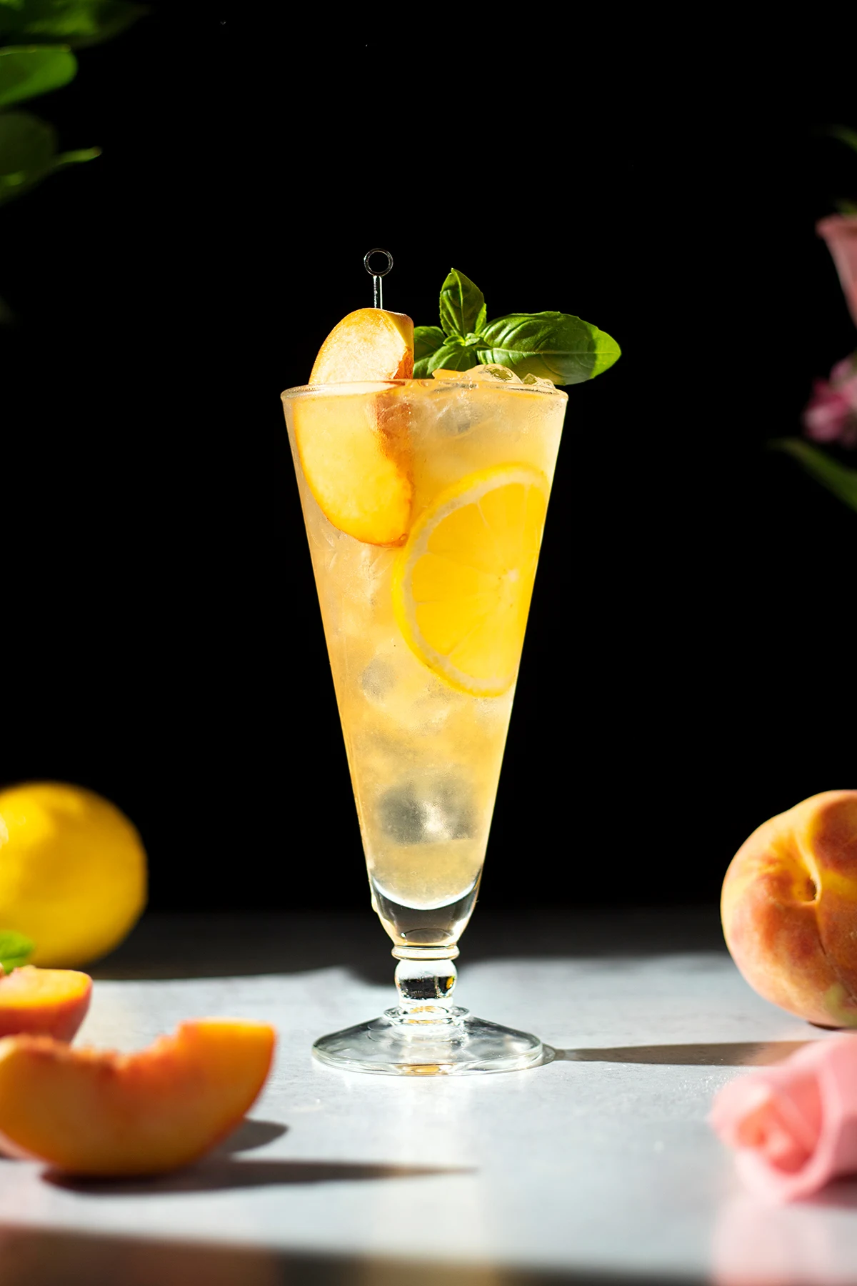 tall glass filled with peach green tea lemonade and peach slice.
