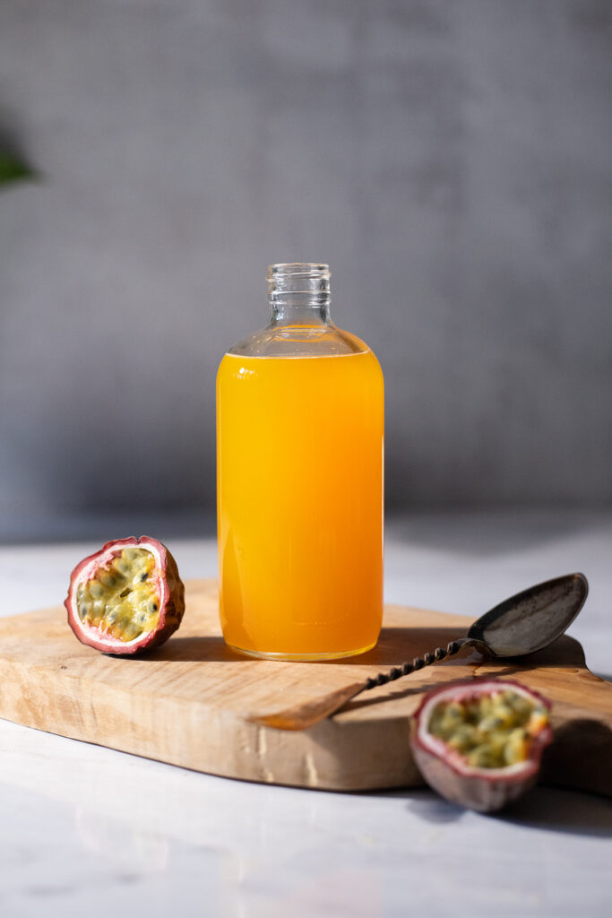 an open glass bottle filled with yellow syrup on a wooden cutting board.