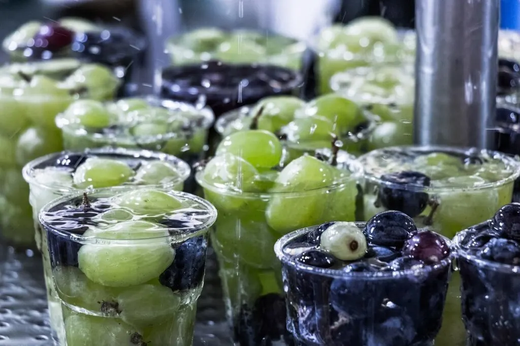 Green and violet grapes in cups with water