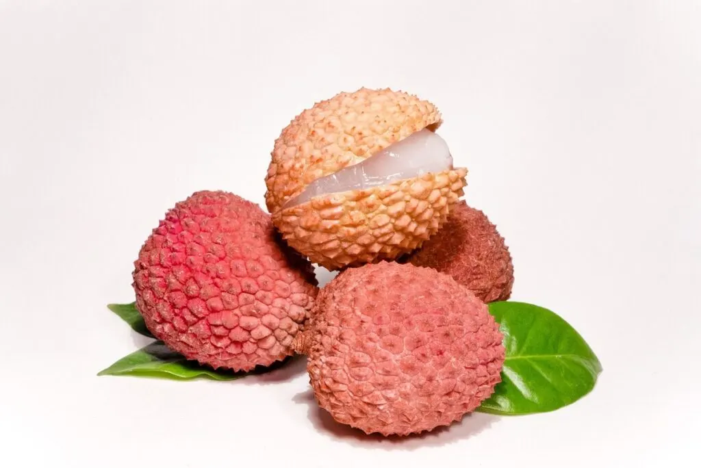 Four lychee fruits with one that is cracked open